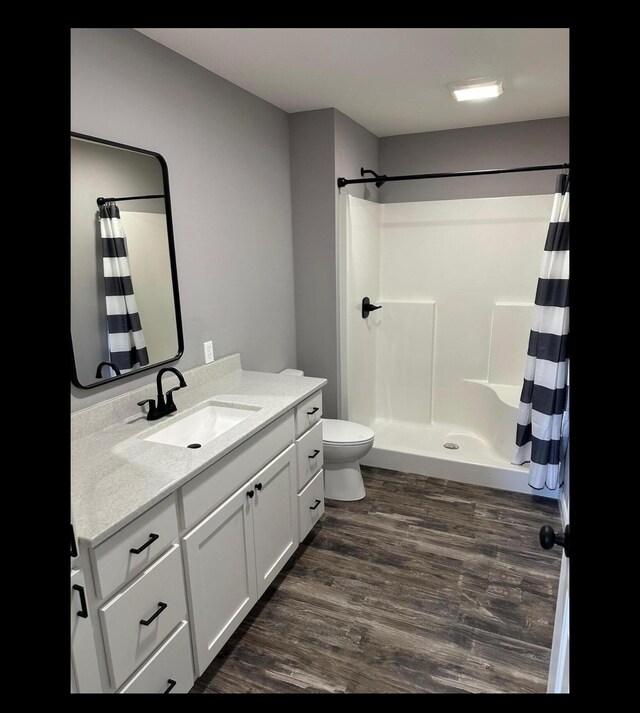 full bathroom featuring toilet, wood finished floors, vanity, and a shower with curtain