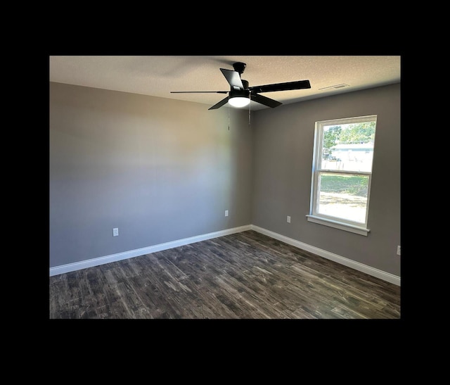 unfurnished room with a textured ceiling, dark wood finished floors, visible vents, and baseboards