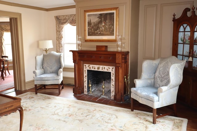 sitting room featuring a tiled fireplace, crown molding, wood finished floors, and baseboards