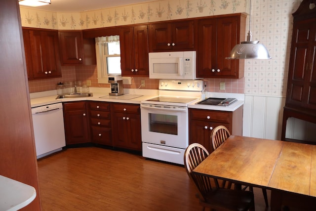 kitchen featuring white appliances, wood finished floors, wallpapered walls, a sink, and light countertops