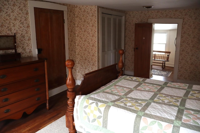 bedroom featuring wallpapered walls, baseboards, and wood finished floors