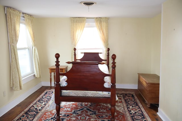 bedroom featuring visible vents, baseboards, and wood finished floors