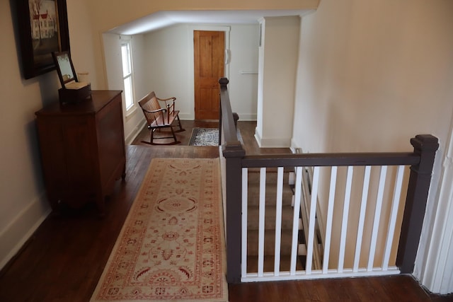 corridor featuring an upstairs landing, baseboards, and wood finished floors