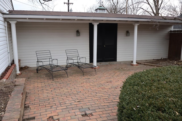 view of exterior entry featuring a patio area and fence