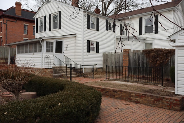 back of property with entry steps, a chimney, and fence