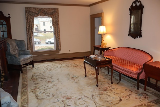 living area featuring baseboards, wood finished floors, and ornamental molding