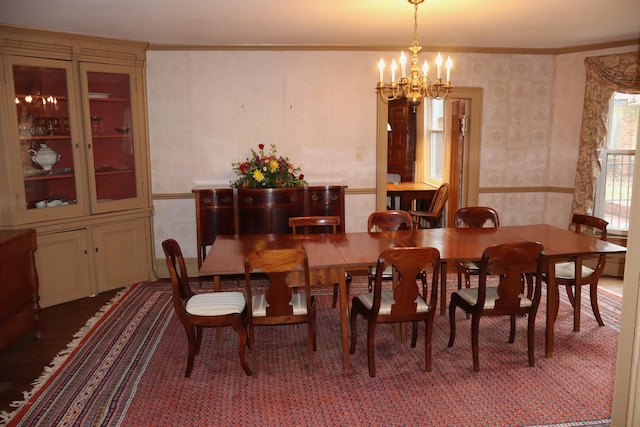 dining room featuring a chandelier, crown molding, and wallpapered walls