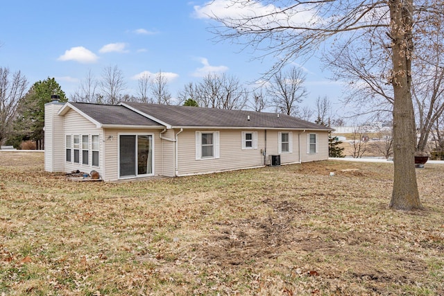 rear view of house featuring a chimney, central AC unit, and a yard