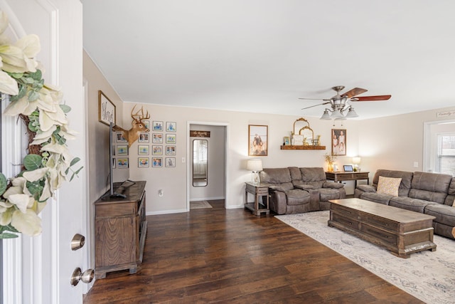 living area featuring baseboards, a ceiling fan, and wood finished floors