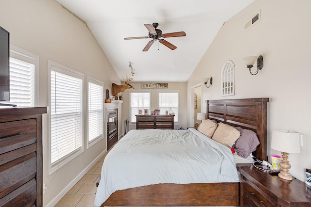 bedroom featuring light tile patterned floors, visible vents, vaulted ceiling, and a glass covered fireplace