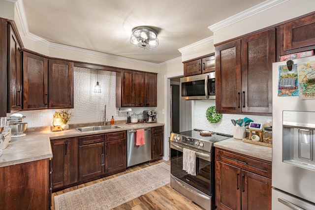 kitchen with light wood-style flooring, stainless steel appliances, a sink, tasteful backsplash, and crown molding