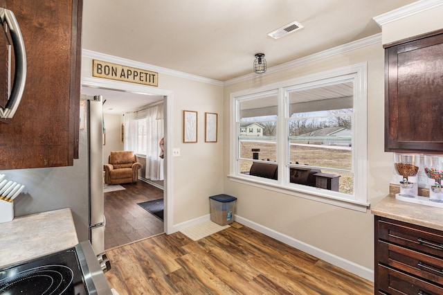 dining area featuring baseboards, wood finished floors, visible vents, and crown molding