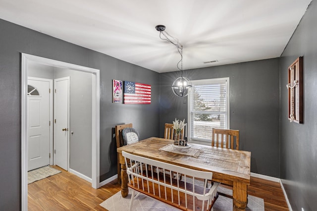 dining area featuring a chandelier, wood finished floors, visible vents, and baseboards