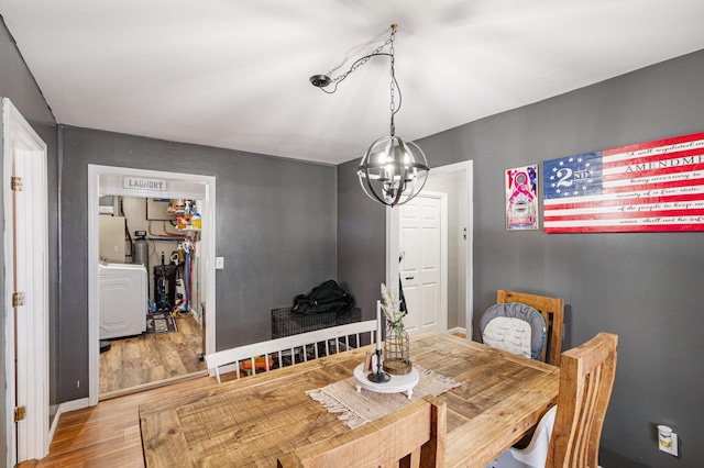 dining area with wood finished floors, washer / dryer, and a notable chandelier