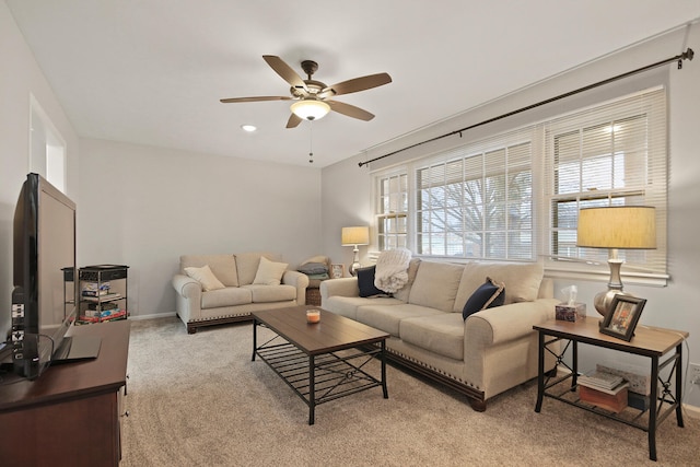 living area with light colored carpet, ceiling fan, and baseboards