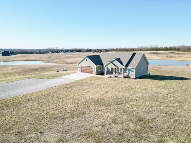 view of front of home with a front yard, a garage, a water view, and driveway