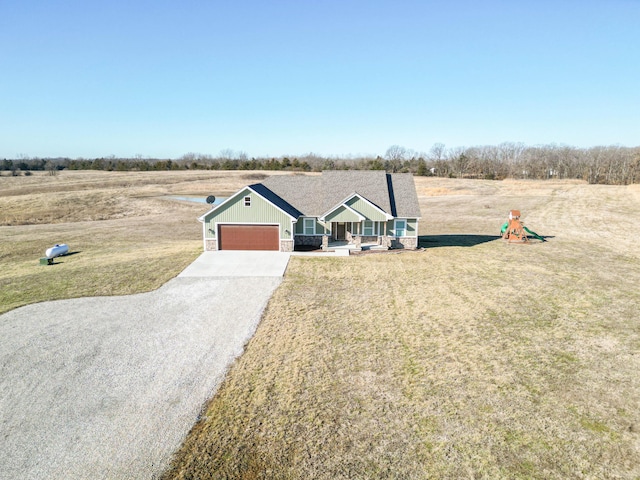 view of front facade featuring covered porch, concrete driveway, a front lawn, a garage, and stone siding