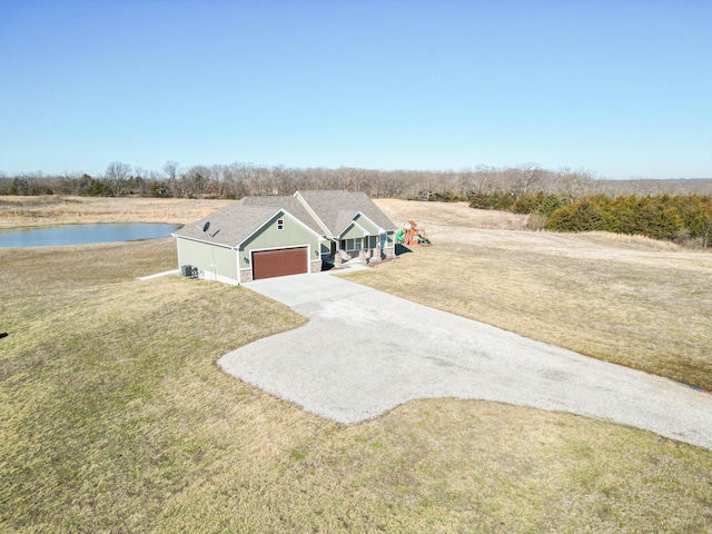 view of front of house with a front lawn, a garage, a water view, and driveway