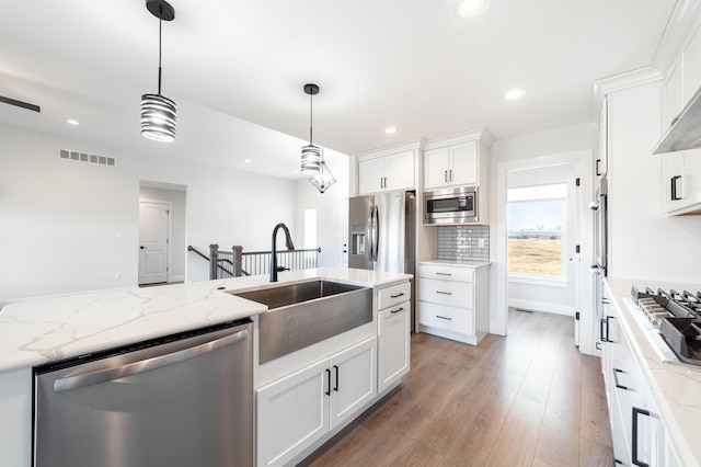 kitchen with tasteful backsplash, visible vents, light wood-style flooring, appliances with stainless steel finishes, and a sink