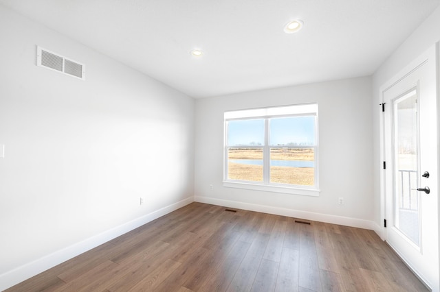 spare room with recessed lighting, visible vents, baseboards, and wood finished floors