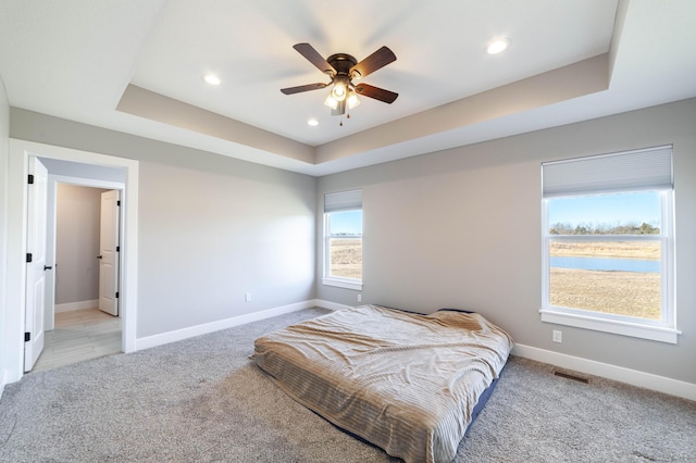 bedroom featuring baseboards, visible vents, a tray ceiling, recessed lighting, and light colored carpet