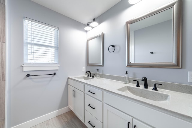 full bathroom featuring double vanity, baseboards, and a sink