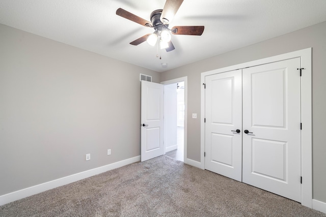 unfurnished bedroom featuring visible vents, baseboards, carpet floors, ceiling fan, and a closet