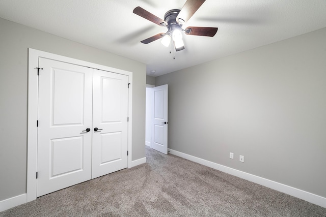 unfurnished bedroom featuring a closet, baseboards, carpet floors, and ceiling fan