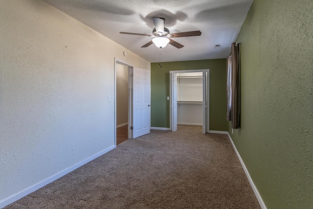 unfurnished bedroom featuring a textured ceiling, baseboards, carpet, and a textured wall