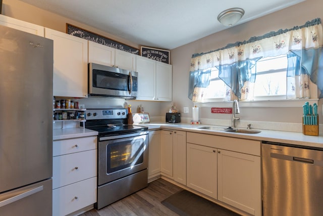 kitchen with dark wood-type flooring, a sink, white cabinetry, appliances with stainless steel finishes, and light countertops