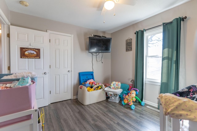 rec room featuring baseboards, ceiling fan, and dark wood-style flooring