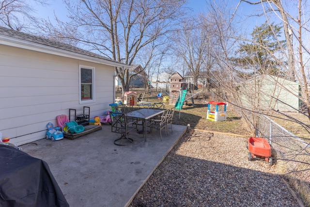 view of yard featuring outdoor dining space, a playground, a patio, and fence