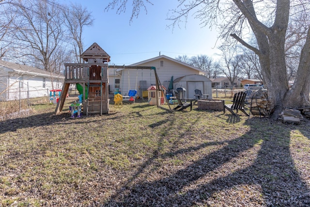 view of jungle gym with a shed, fence, a yard, a fire pit, and an outdoor structure