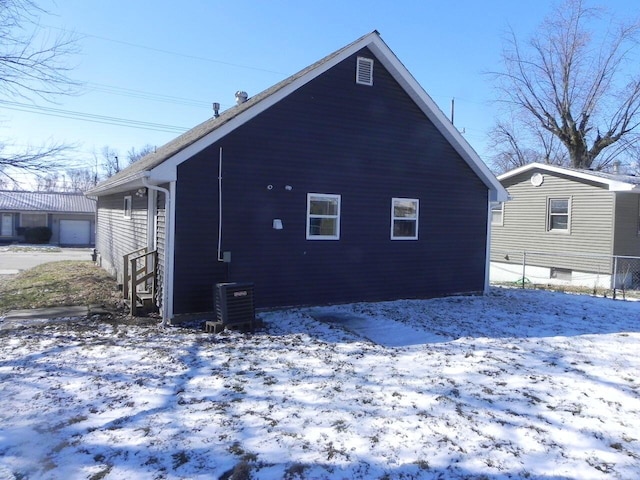 snow covered property featuring an outdoor structure and central AC unit