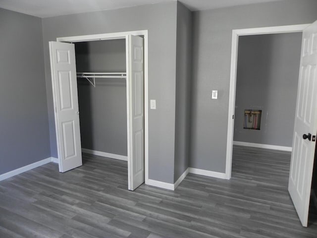 unfurnished bedroom featuring a closet, baseboards, and dark wood-style flooring