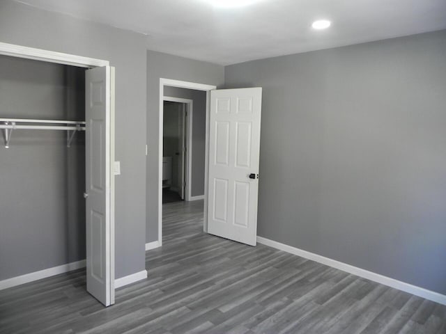 unfurnished bedroom featuring a closet, baseboards, wood finished floors, and recessed lighting