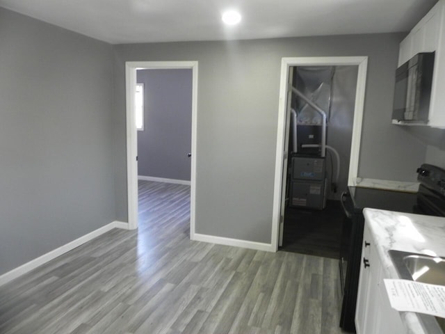 kitchen featuring baseboards, white cabinetry, black appliances, and wood finished floors