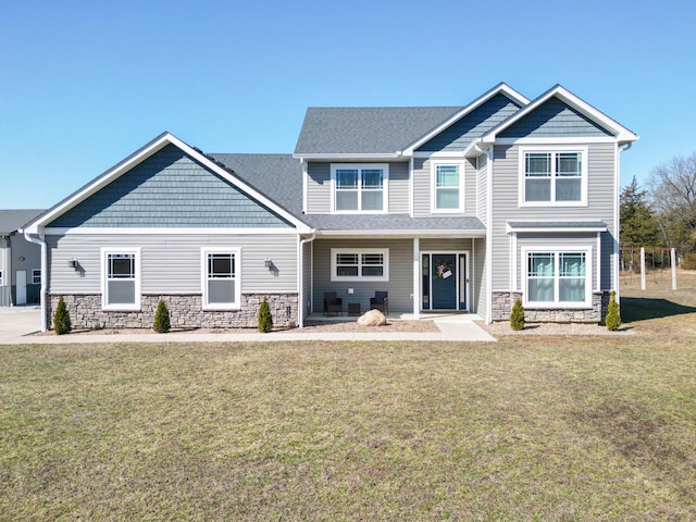 craftsman-style house with stone siding, a front lawn, and a shingled roof