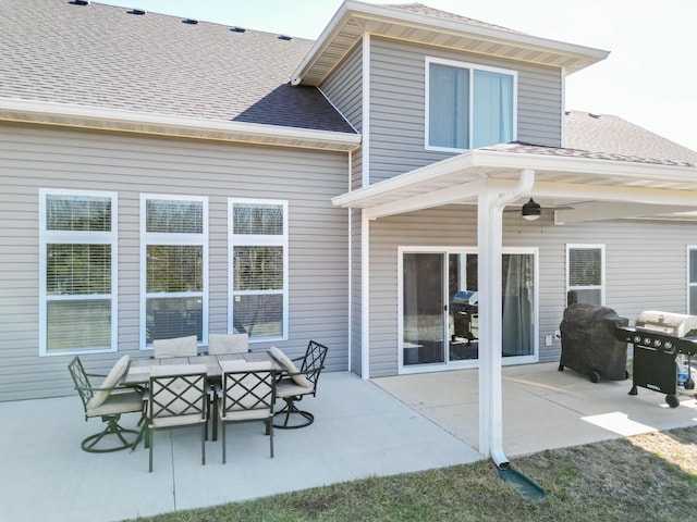 rear view of house with a patio, a shingled roof, and outdoor dining space