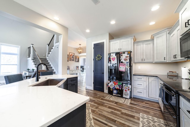 kitchen featuring recessed lighting, dark wood-type flooring, a sink, black appliances, and an inviting chandelier