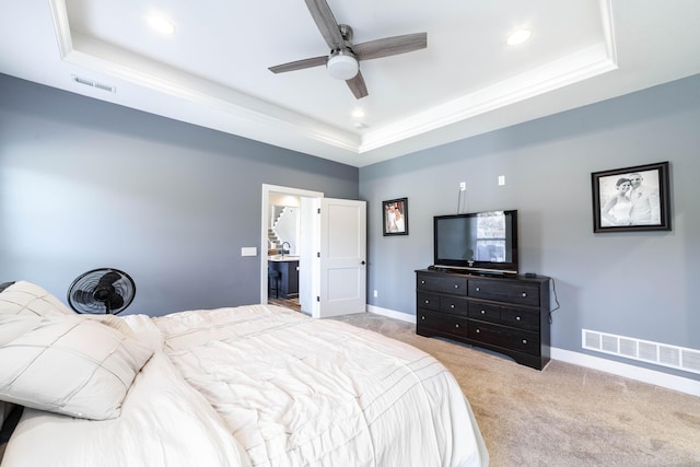 bedroom with a tray ceiling, visible vents, light carpet, and baseboards