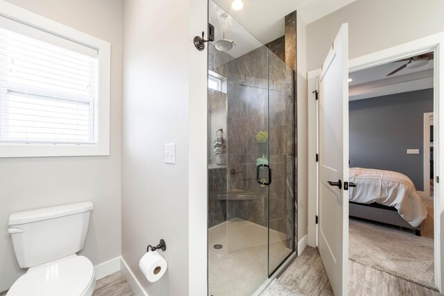 bathroom with toilet, a stall shower, connected bathroom, wood finished floors, and baseboards