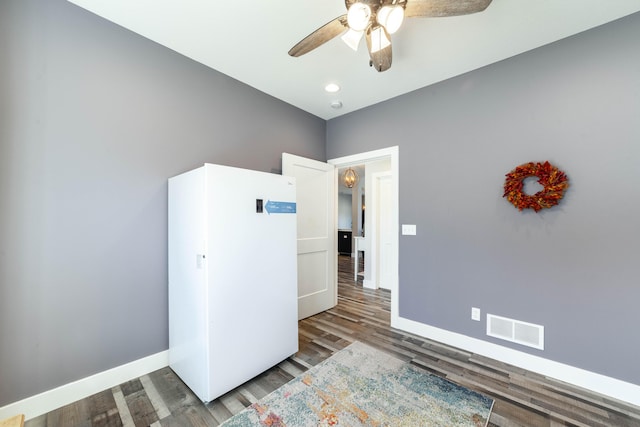 empty room with a ceiling fan, visible vents, baseboards, and wood finished floors