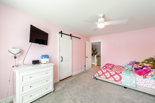 bedroom with light carpet, ceiling fan, a barn door, and baseboards