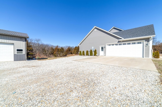 view of property exterior featuring roof with shingles, concrete driveway, board and batten siding, a standing seam roof, and metal roof