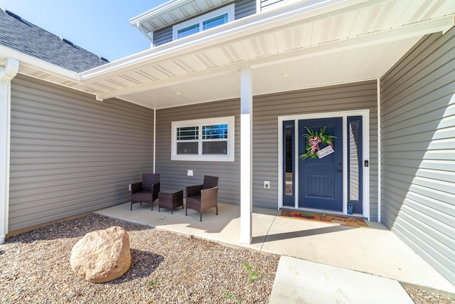 entrance to property with covered porch and roof with shingles