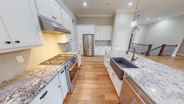 kitchen featuring under cabinet range hood, stainless steel appliances, a sink, white cabinetry, and light wood-style floors