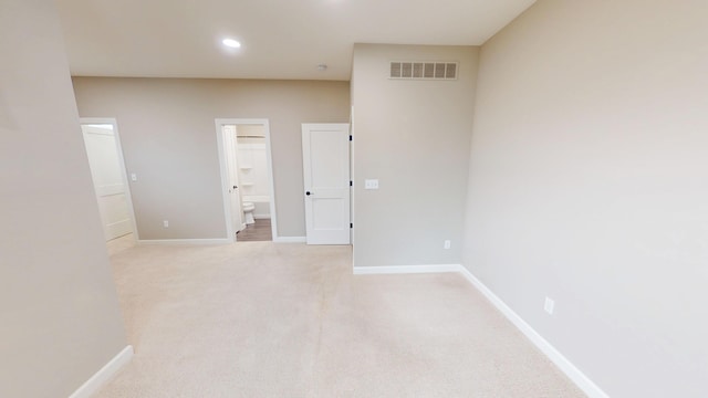 spare room featuring light colored carpet, visible vents, and baseboards