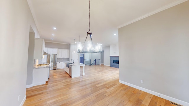 kitchen featuring ornamental molding, open floor plan, backsplash, and freestanding refrigerator