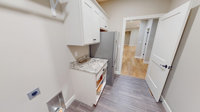 interior space featuring light wood finished floors, cabinet space, baseboards, and hookup for an electric dryer